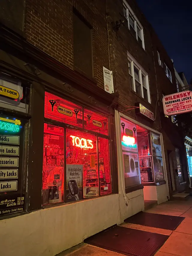 Wilensky's shopfront at night: red-lit windows, a TOOLS neon sign and the hanging blade sign