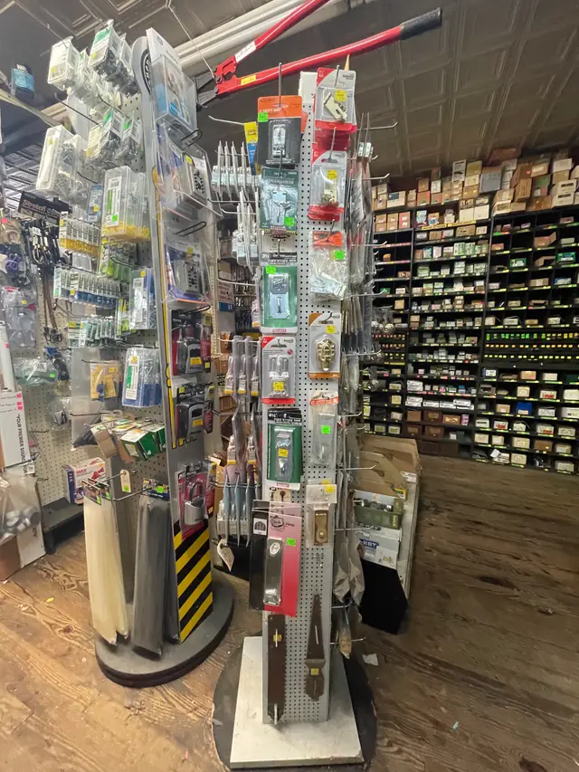 Hardware aisle with a spinner rack of hooks and packaged parts in front of wall bins